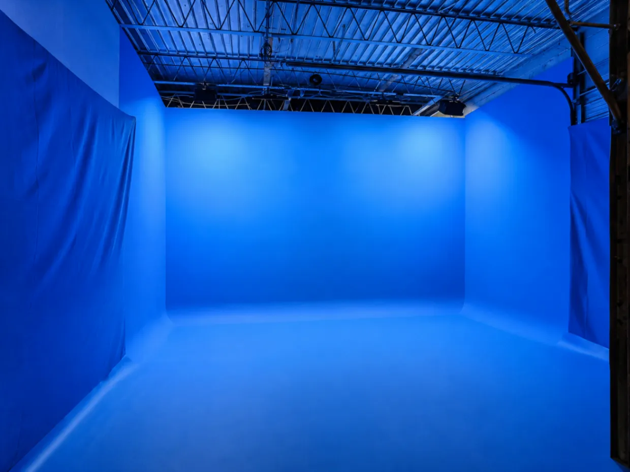 Blue cyclorama studio with overhead lighting and draped side walls