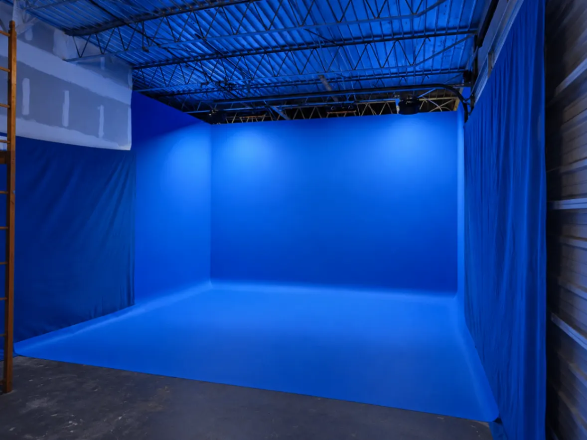 Blue cyclorama studio framed by draped side walls and production access