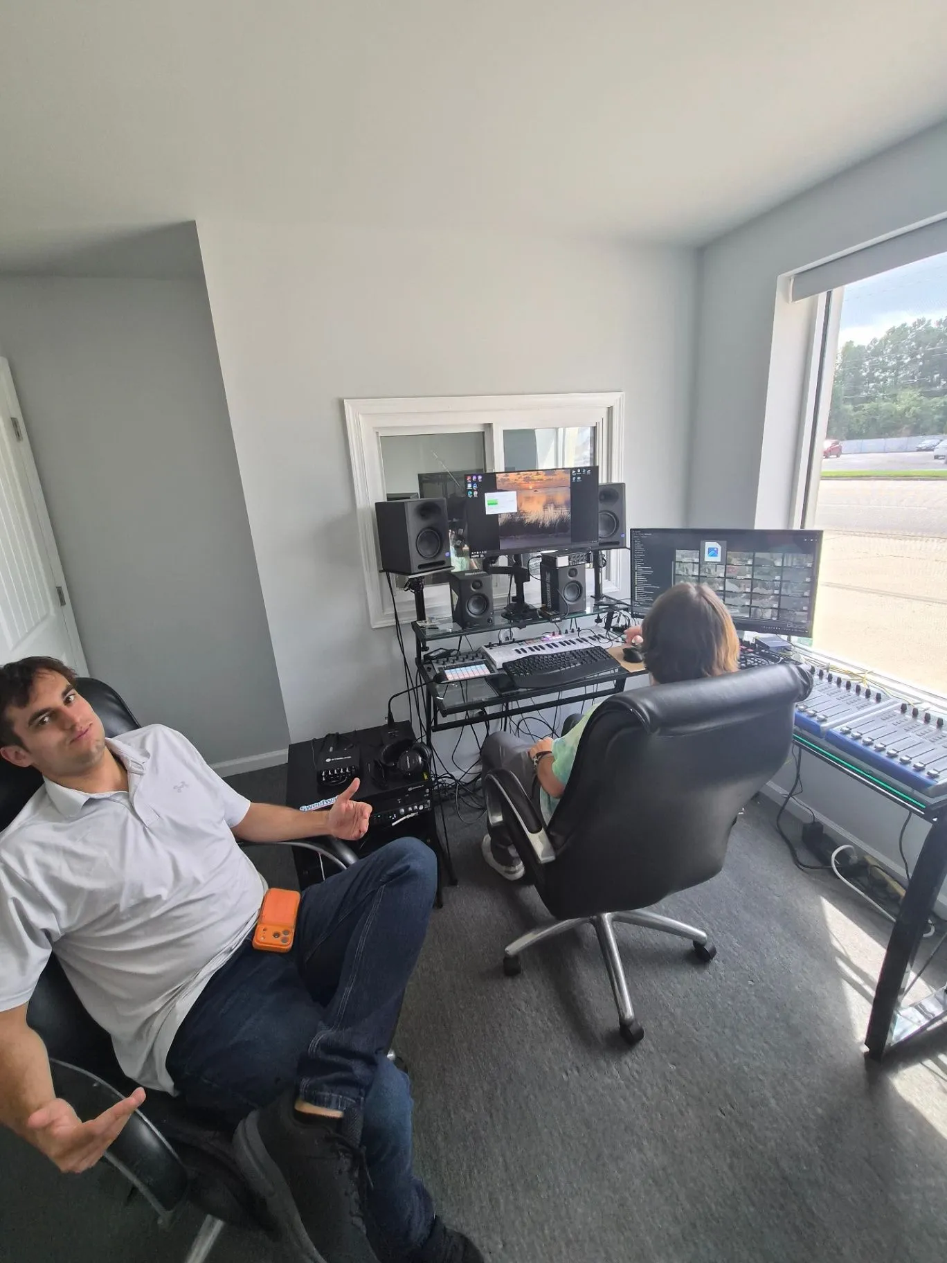 Editing and mixing room with monitors, speakers, a keyboard, and a mixing console